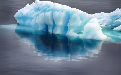 Floating blue iceberg with deep grooves reflected in calm Arctic waters, highlighting the icy environment of polar seas like the Kara Sea.